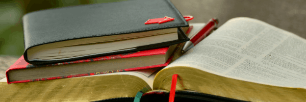 two-closed-books-resting-on-top-of-an-open-bible